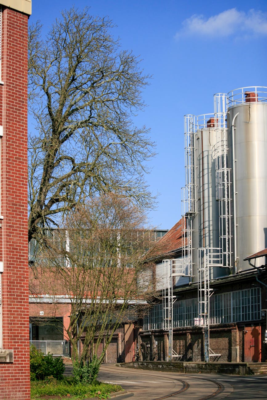 A futuristic, high-tech facility with visible pipes and tanks, showcasing a massive industrial process with a backdrop of a clean, vibrant cityscape under a clear blue sky.