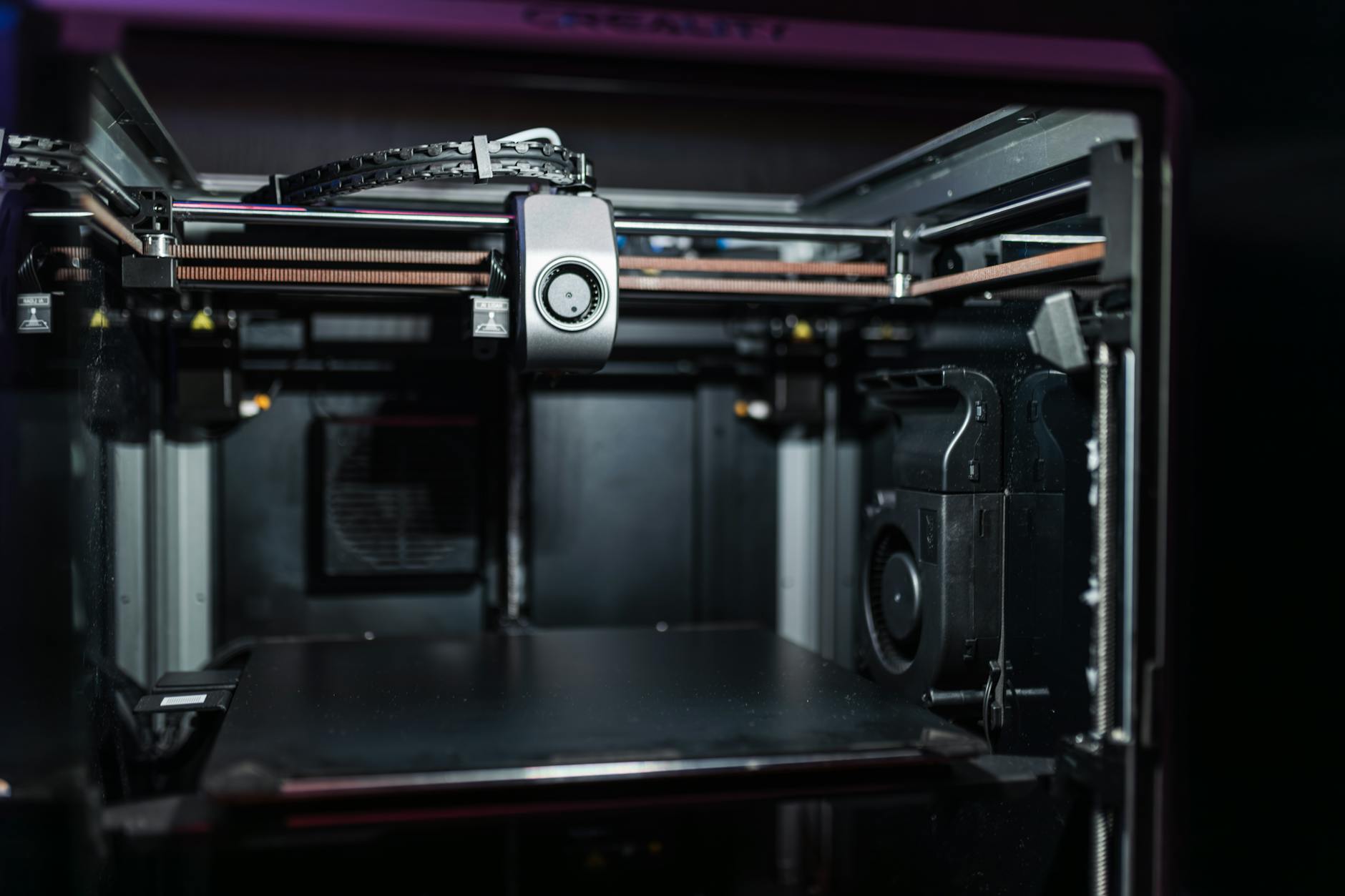 A 3D printer operating autonomously within a space station module, fabricating intricate metallic components.