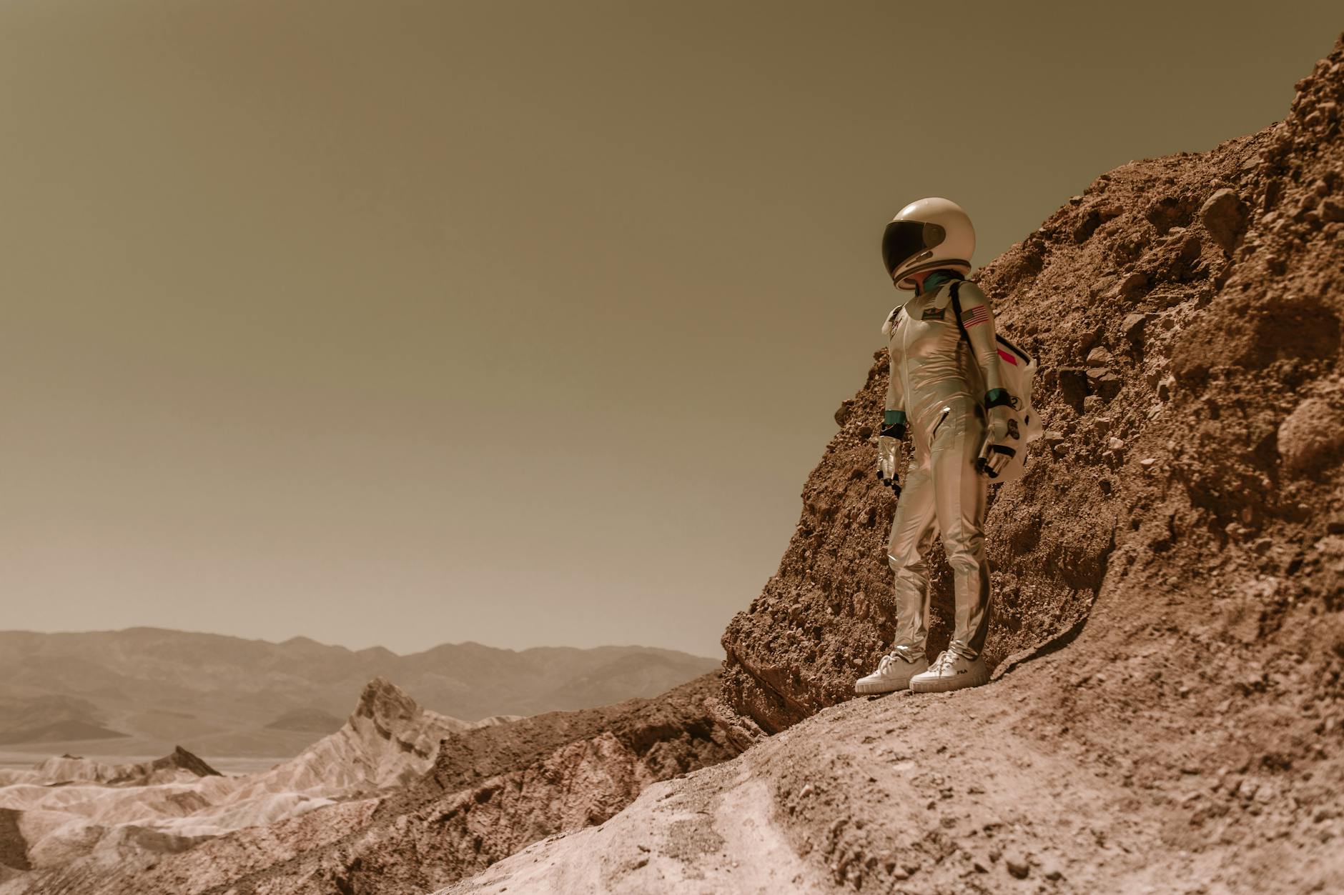 A futuristic, sleek autonomous robot with glowing blue optical sensors exploring a Martian landscape, with Earth visible in the distant sky.