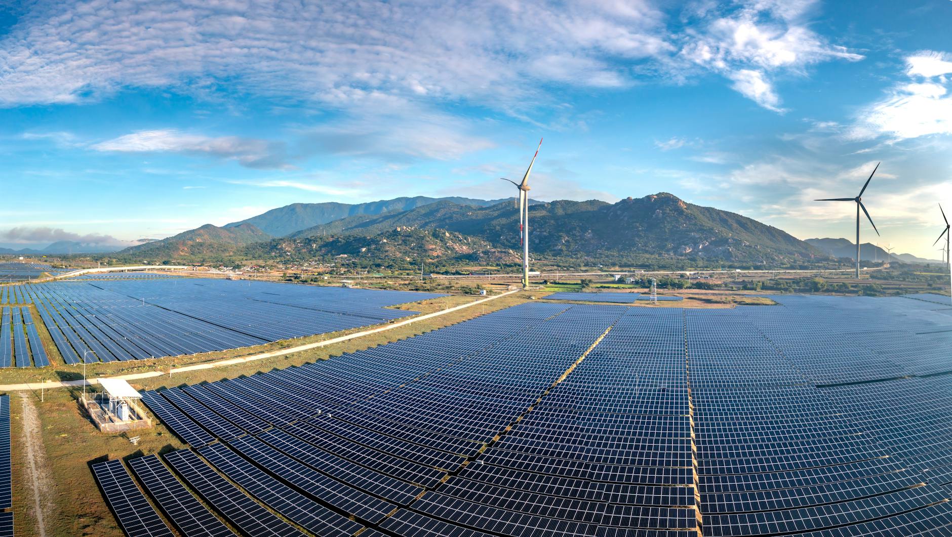 A panoramic shot of a large-scale LDES facility, perhaps a pumped-hydro plant or a vast array of flow battery containers, emphasizing its integration with nearby wind turbines or solar farms.