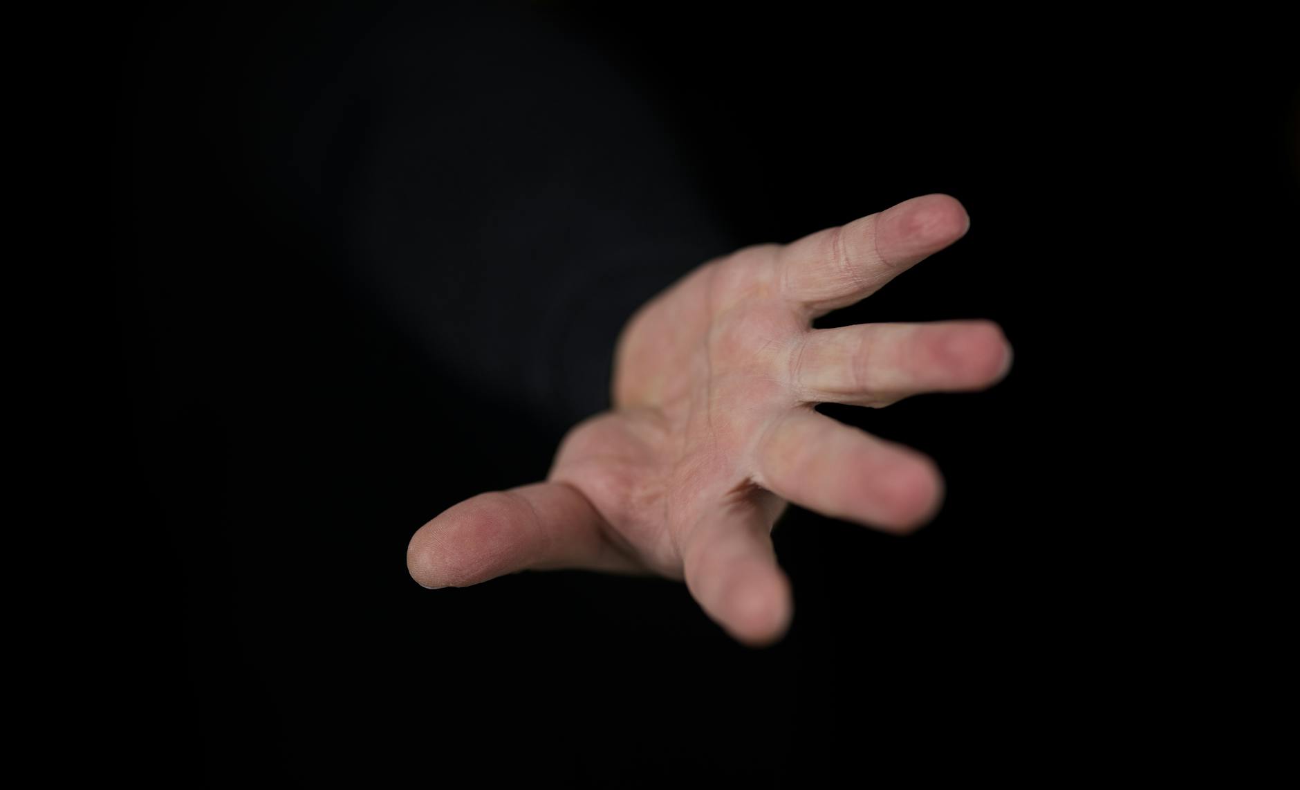 A stark, conceptual image of a single human hand reaching out to a vast, incomprehensible, glowing AI entity, symbolizing the control problem and existential risk.