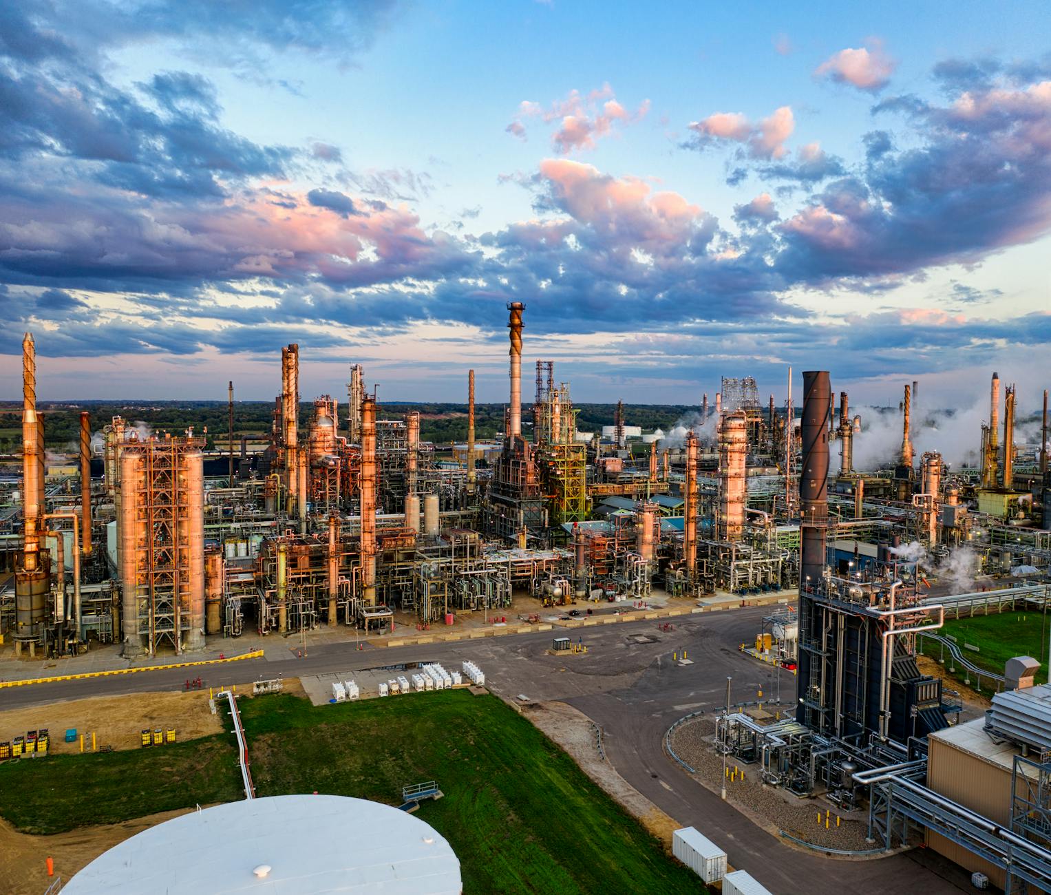 A split image showing on one side, the complex industrial processes of heavy industry, and on the other, a conceptual representation of captured CO2 being transformed into sustainable aviation fuel.