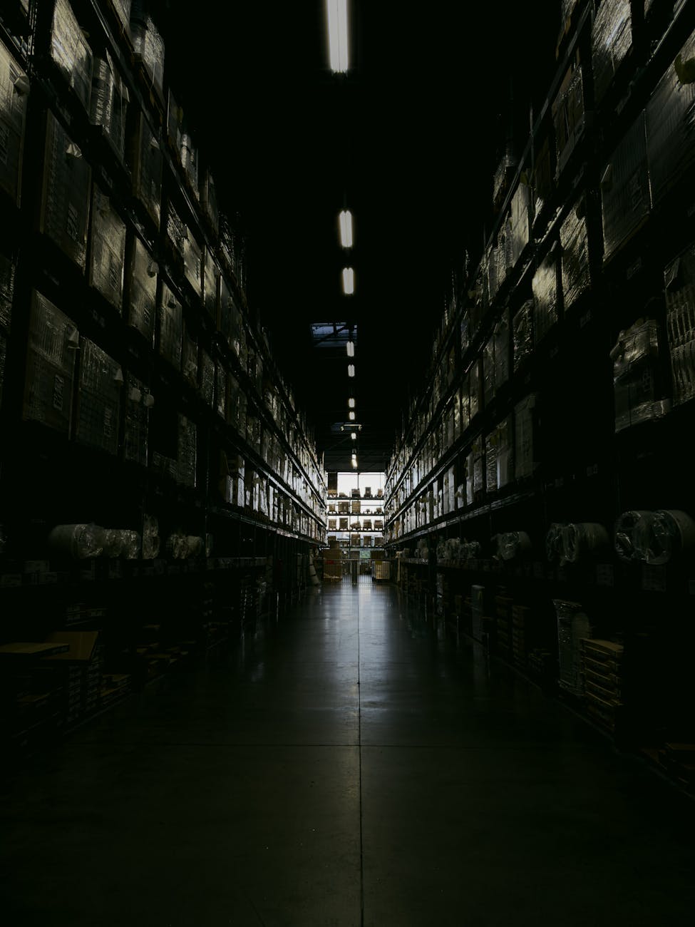 A panoramic, high-resolution shot of a fully automated logistics hub at night, seen from a slightly elevated perspective. Hundreds of AMRs, resembling glowing ants, are meticulously moving goods under the soft glow of smart lighting. The scene conveys a sense of complex, synchronized efficiency and futuristic scale.