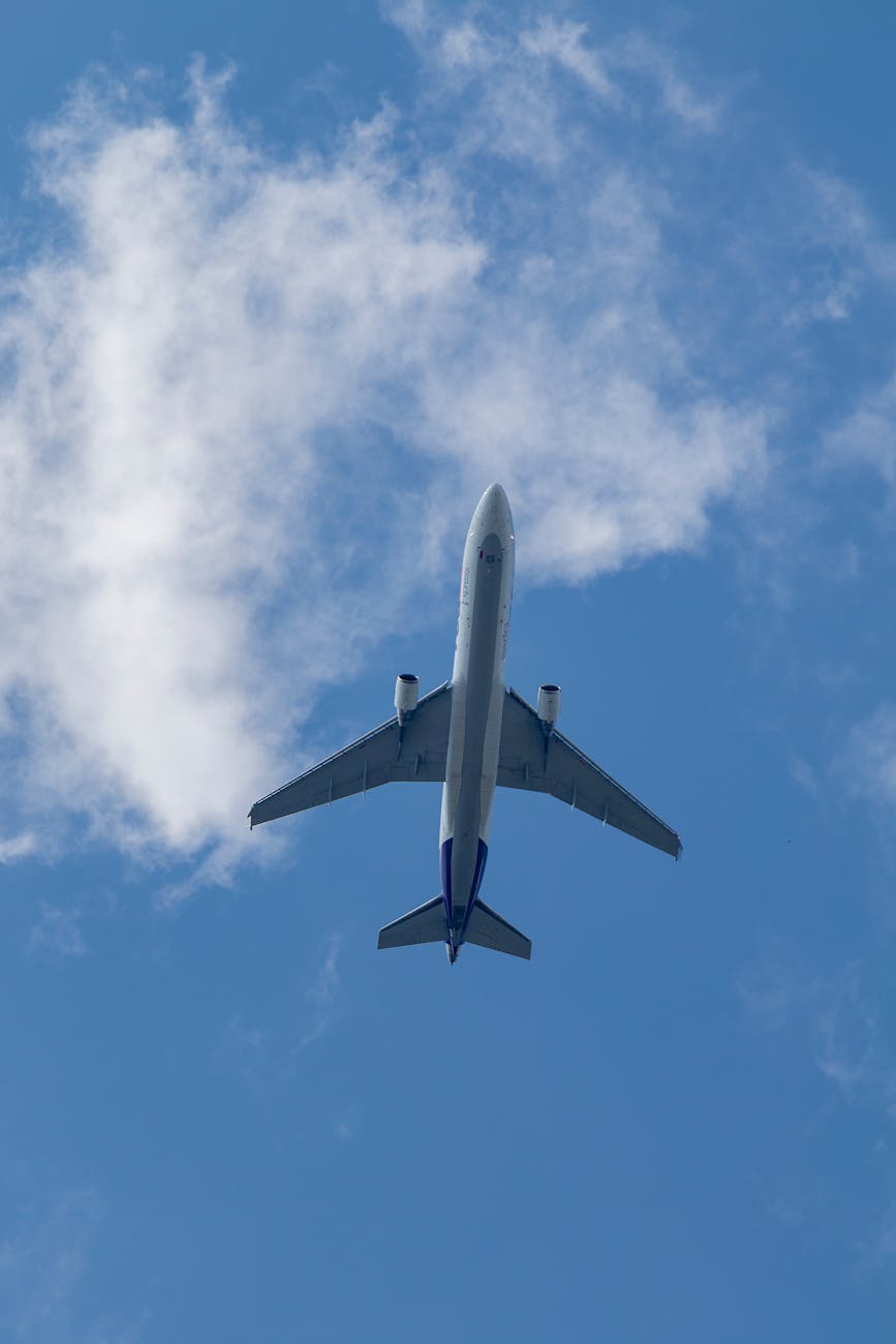 A futuristic, sleek commercial aircraft with visible sustainable design elements, soaring gracefully above a pristine, cloud-dappled landscape at sunrise. The contrails are minimal, hinting at low emissions. The image evokes a sense of hope and advanced technology.