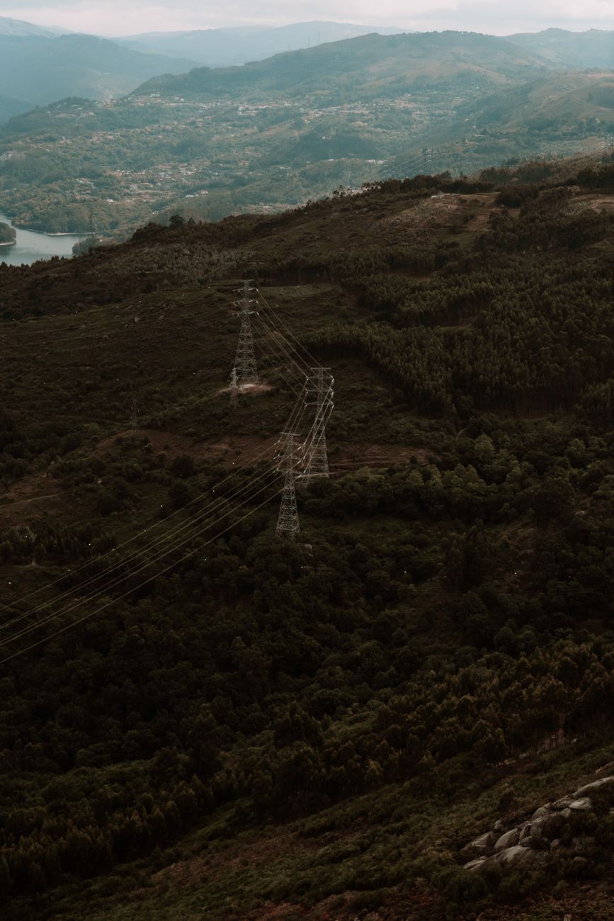 A majestic, sweeping landscape view of a clean energy landscape at dusk, with subtle, integrated EGS facilities and glowing AI network lines connecting them.