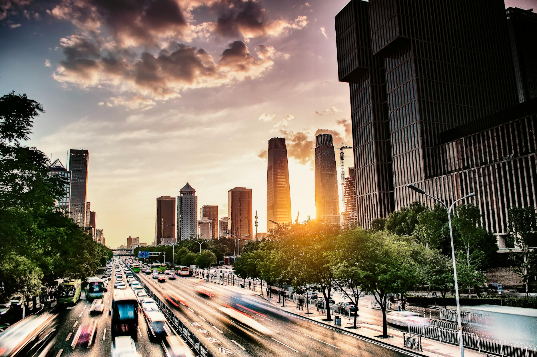 A futuristic cityscape at dusk, with sleek eVTOL aircraft gracefully navigating designated sky-lanes between towering skyscrapers. The city below is bustling with traditional transport, highlighting the contrast and the emergence of a new aerial dimension.